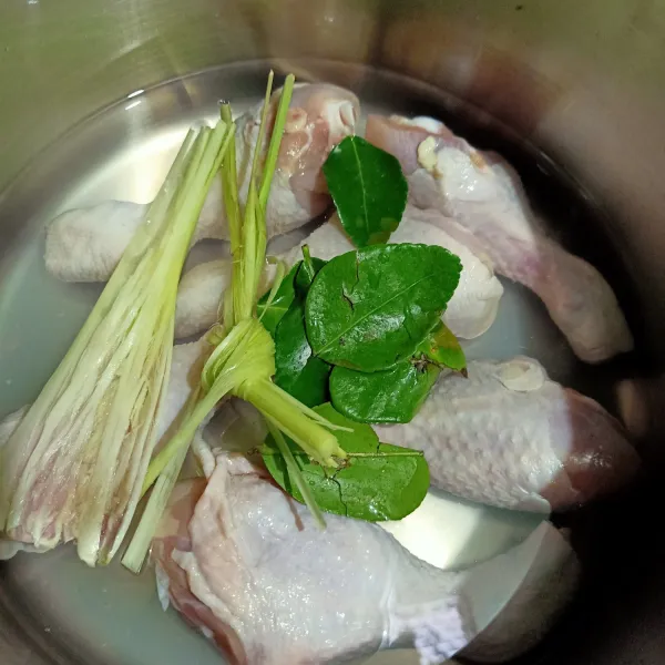 Siapkan panci lalu masukkan ayam, air kelapa, daun jeruk, dan serai ke dalam panci.