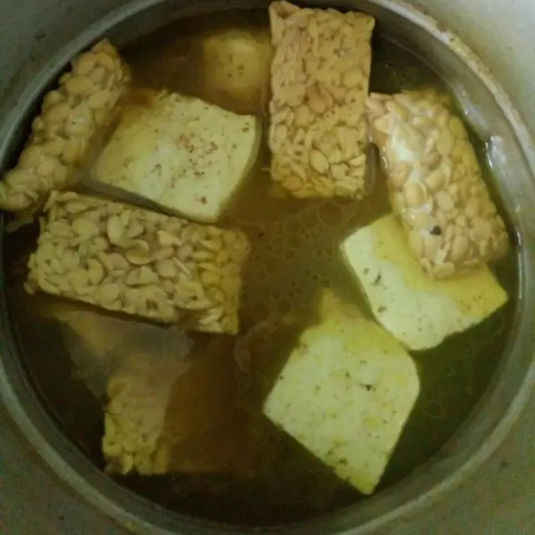 Saat ayam setengah matang, masukkan tahu dan tempe. Masak kembali hingga matang dan air habis.  Lalu tiriskan.