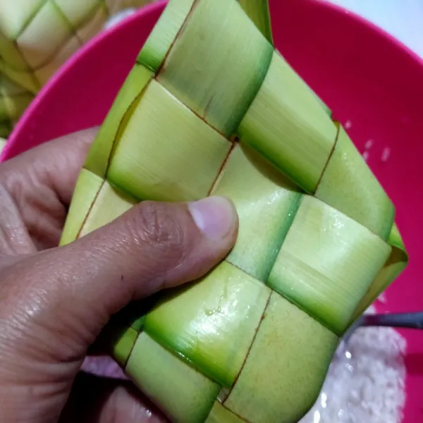Isi sarang ketupat dengan beras sampai setengah bagian.
