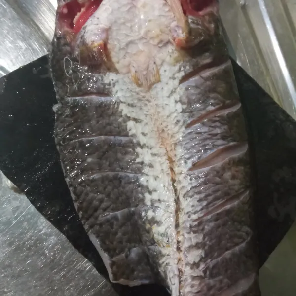 Siangi ikan haruan, belah dari bagian atasnya lalu kerat daging ikan haruan di kedua sisinya