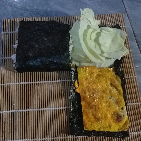 Lipat nori mulai dari bagian nasi ke telur kemudian ke arah kubis dan terakhir ke telur bawah.