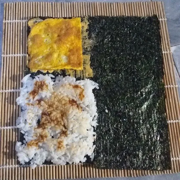 Letakkan nasi tepat disamping bagian yang digunting, ratakan kemudian olesi dengan sambal. Di bagian atas nori beri sedikit mayonaise lalu timpa dengan telur dadar.