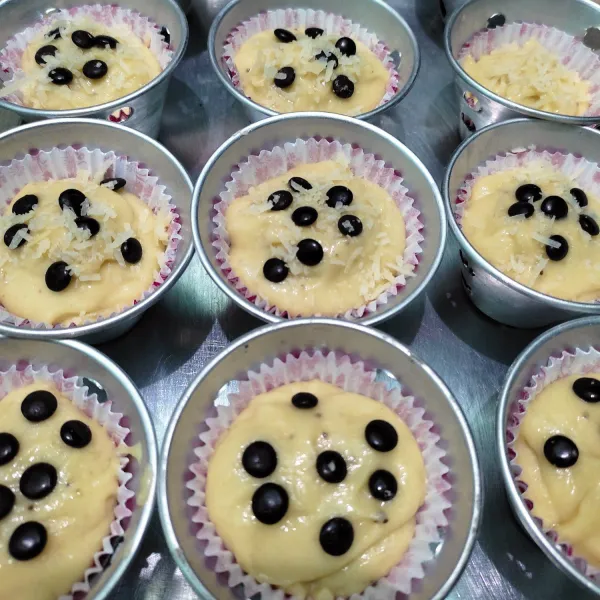 Masukkan adonan ke dalam paper cup, isi 3/4 bagian. Kemudian beri toping choco chip dan keju parut.