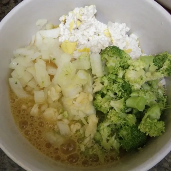 Dalam mangkuk, campurkan kocokan telur ayam, cincangan brokoli, bawang putih, bawang bombay dan tahu, aduk rata