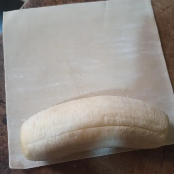 Letakkan pisang yang sudah di kupas di atas kulit pangsit.