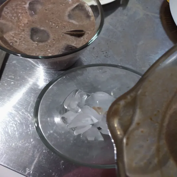 Siapkan gelas saji, beri es batu secukupnya. Tuang hasil yang di blender lalu taburi coklat bubuk di atasnya. Sajikan.