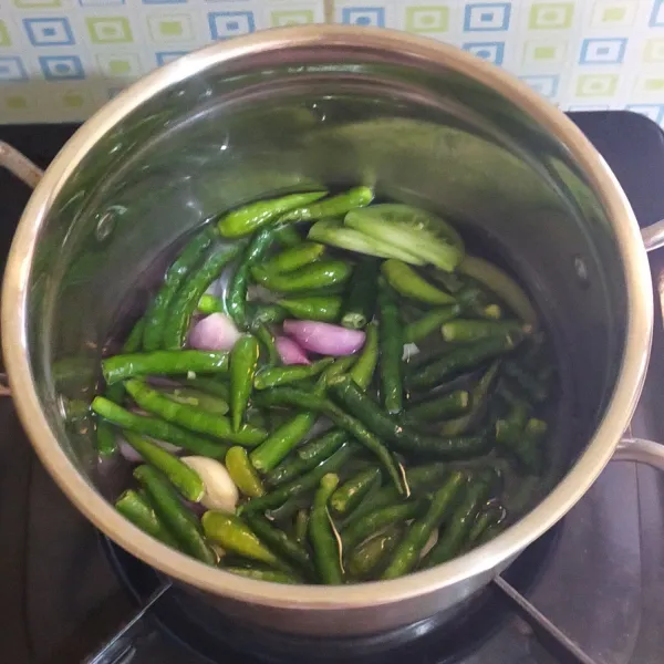 Didihkan air, rebus cabe hijau, cabe rawit, bawang merah, bawang putih dan tomat sekitar 5 menit lalu angkat dan tiriskan.