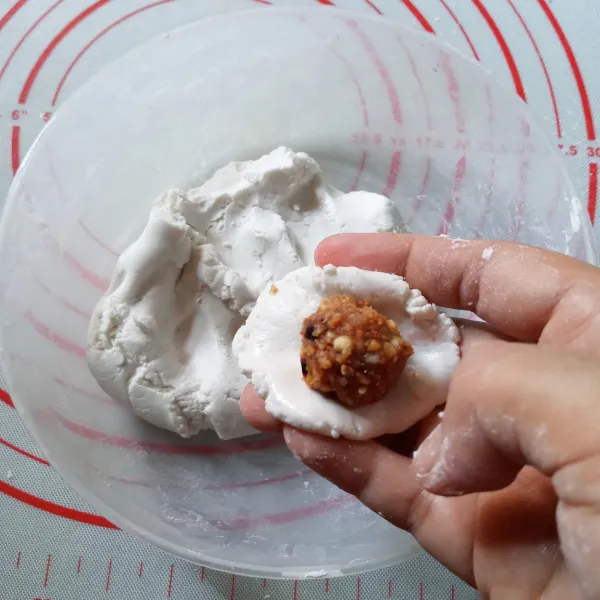 Ambil adonan kulit, pipihkan. Beri isian kacang tanah lalu bulatkan. Lakukan sampai selesai.