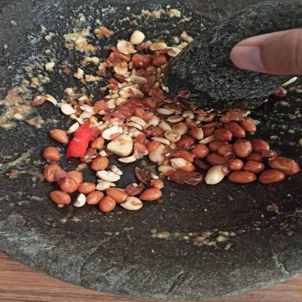 Siapkan ulekan, ambil 3 sdm kacang tanah yang sudah digoreng, tambahkan cabai sesuai selera dan 1/2 buah bawang putih, haluskan hingga cukup halus.