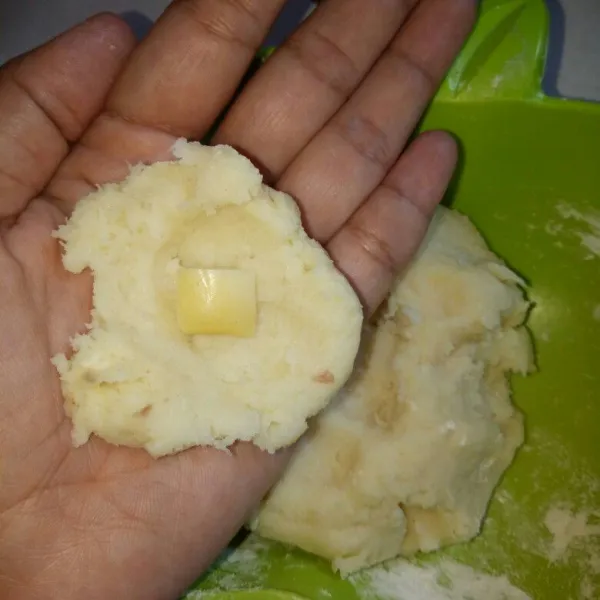 Ambil 1 sdm adonan tape, pipihkan lalu isi dengan keju potong. Bentuk sesuai selera