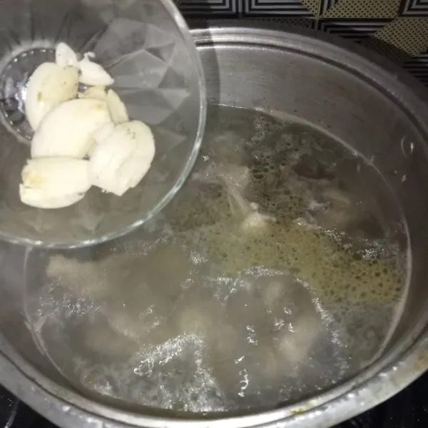 Setelah mendidih masukkan bawang putih dan jahe. Masak hingga ayam matang.