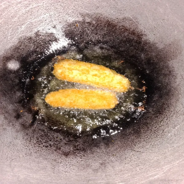Goreng pisang yang telah dilumuri tepung roti ke dalam wajan dengan minyak panas