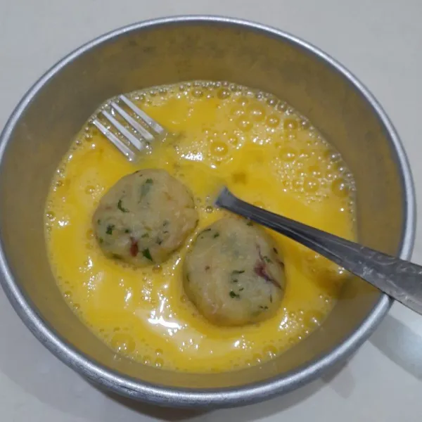 Celupkan bulatan kentang ke dalam kocokan telur, sambil di bolak balik. 
Lakukan berulang sampai adonan kentang habis.