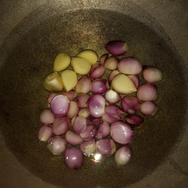 Tuang minyak diwajan, masukkan juga bawang merah dan bawang putih, rendam dalam minyak selama 10 menit.