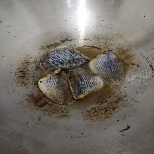 Rendam ikan asin dalam air hangat, diamkan sebentar. Kemudian, goreng ikan asin hingga matang.