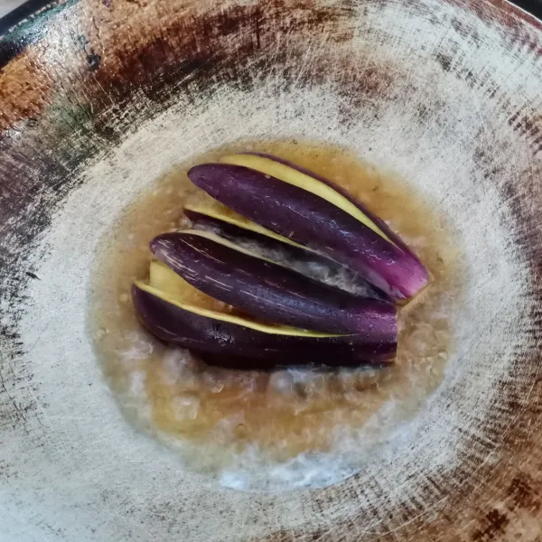 Belah terong menjadi 4 bagian jangan sampai putus. Kemudian goreng terong sampai matang.