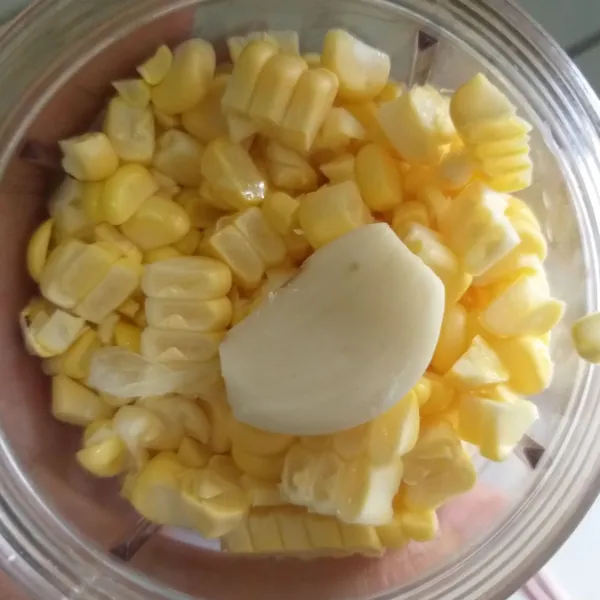 Bagi dua jagung pipil, untuk dihaluskan dengan bawang putih, dan sisanya dibiarkan tetap utuh.