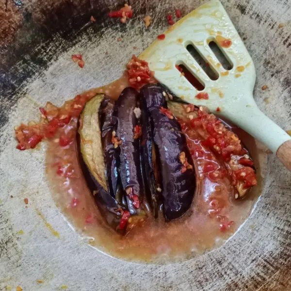 Masukkan terong, aduk rata. Beri air, aduk rata kembali.