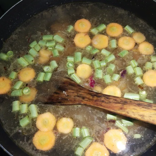 Kemudian masukkan air kaldu dan masukkan wortel beserta buncis. Masak hingga wortel dan buncis menjadi empuk.