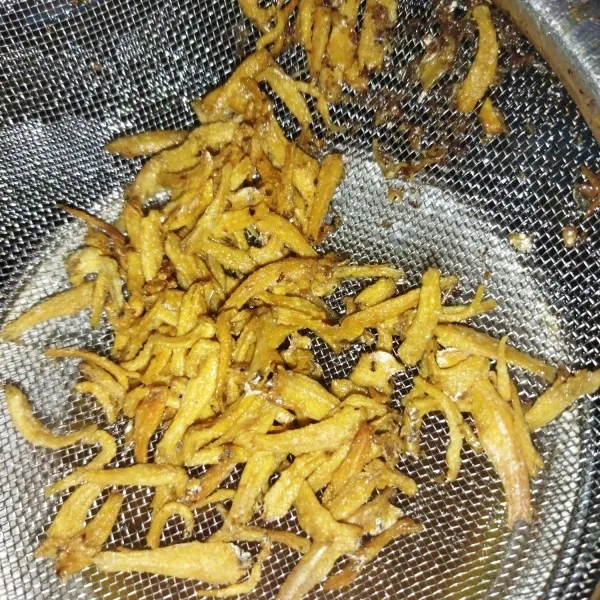 Siapkan ikan teri asin, buat kepalanya, cuci dengan sekali bilas lalu goreng hingga garing.