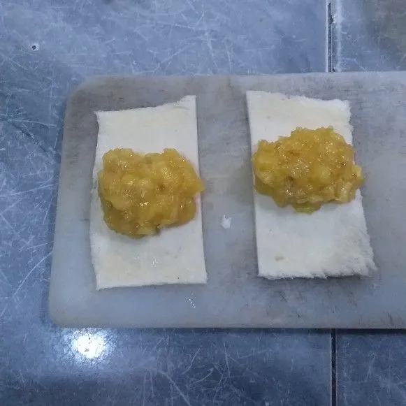 Oles bagian pinggir roti di kedua sisi dengan telur, tambahkan pisang secukupnya, kemudian gulung. baluri dengan kocokan telur.