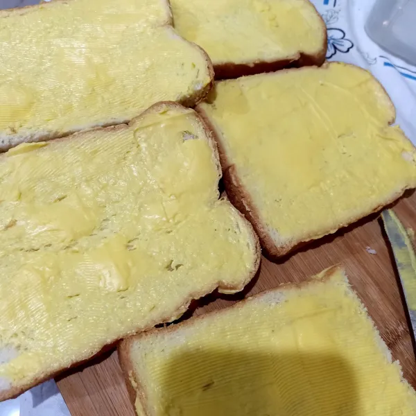 Ambil roti tawar, kemudian oles tipis margarin pada permukaan roti. Kemudian bagi 2.