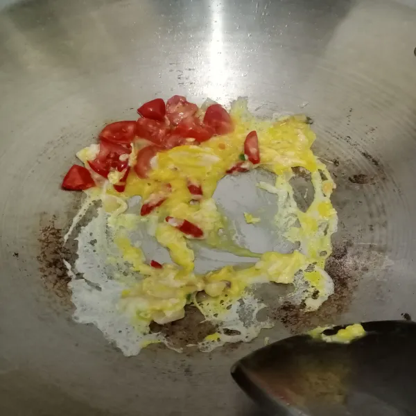 Tumis bawang dan cabai hingga wangi. Masukkan telur dan tomat, kemudian aduk rata.