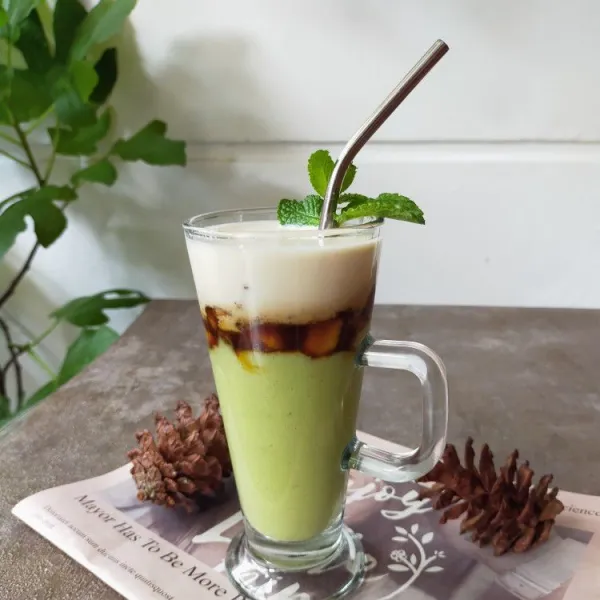 Tata blenderan alpukat dan pisang karamel di gelas saji, kemudian siram dengan susu cair dingin. Hias sesuai selera, kemudian sajikan.