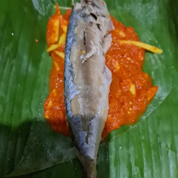 Beri bumbu di dasar daun lalu beri ikan pindang.