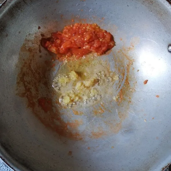 Sisihkan tomat dipinggir wajan, tambahkan minyak, kemudian tumis bumbu halus hingga harum.