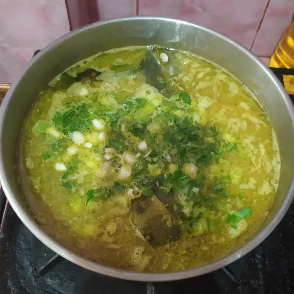 Sembari menggoreng ayam, masukkan irisan daun bawang dan seledri ke dalam kuah soto. Tes rasa.