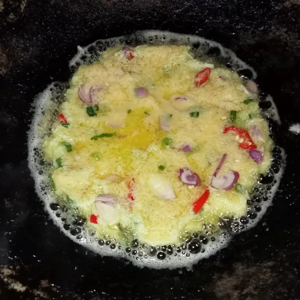 Panaskan minyak goreng diwajan, lalu tuang adonan telur dan ratakan. Masak dengan api kecil saja.