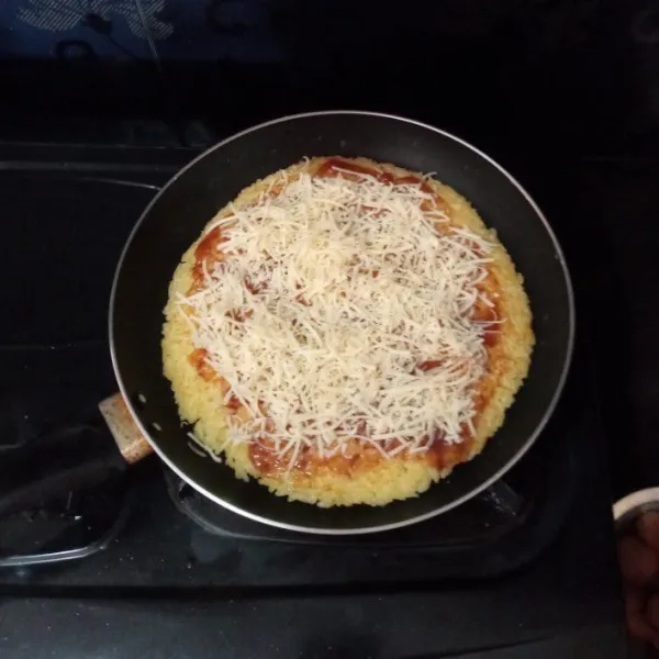 Masukkan saus pizza/ saus tomat di atas dadar nasi ratakan, lalu mayonaise, ratakan, kemudian keju cheddar.
