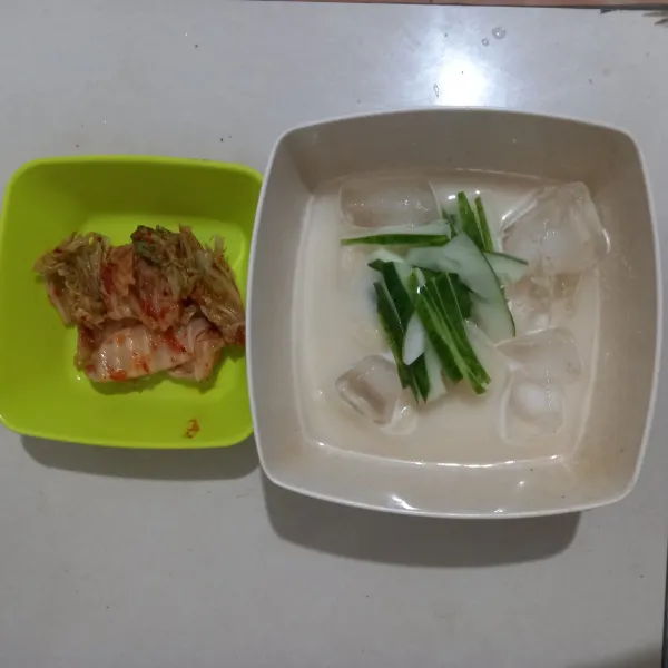 Siapkan mangkuk lalu masukkan mie, kuah kedelai, timun, dan tambahkan es batu secukupnya. Sajikan kimchi sebagai pendamping.