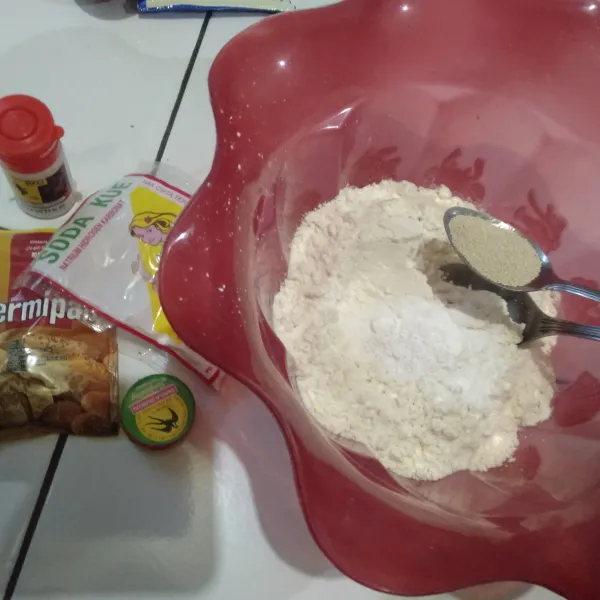Siapkan bahan-bahan yang dibutuhkan, lalu masukkan tepung terigu ke dalam wadah dan tambahkan fermipan, baking powder, soda kue, vanili bubuk, gula pasir dan sejumput garam, aduk hingga rata.