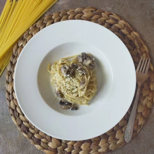 Sajikan hangat pasta Alfredo dengan taburan parsley.