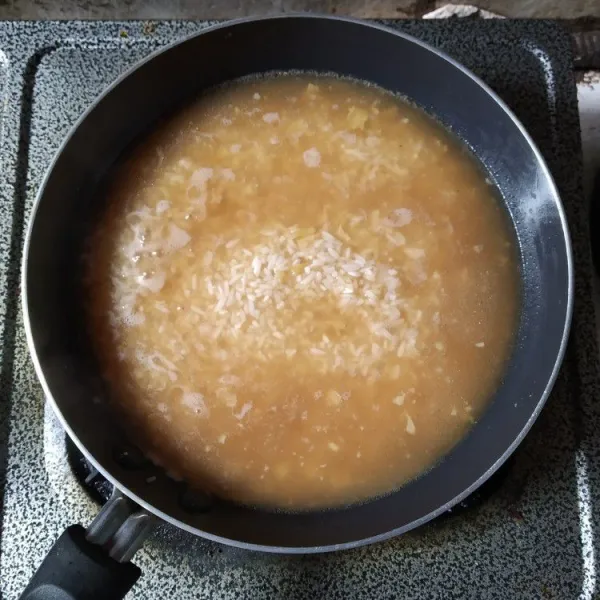 Masukkan beras, tambahkan air kaldu dan kecap asin, biarkan mendidih.