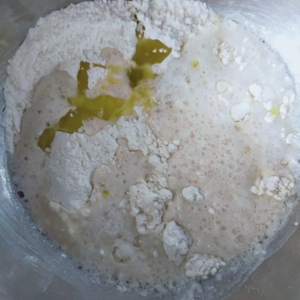 Dalam wadah lain masukkan tepung terigu, garam, air ragi dan minyak zaitun.