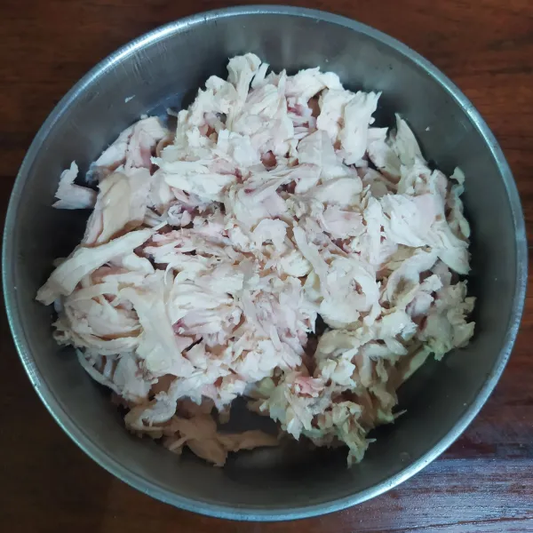 Rebus dada ayam hingga matang, lalu tiriskan. Setelah dingin, suwir-suwir daging ayam. Sisihkan air rebusannya sebanyak 200 ml.