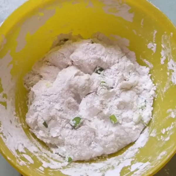 Campurkan tepung tapioka, daun bawang, dan semua bumbu. Kemudian masukkan air panas sedikit demi sedikit hingga menjadi adonan basah. Kemudian tuang tepung terigu sambil di uleni hingga kalis.