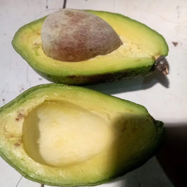 Belah buah alpukat, lalu buang bijinya.