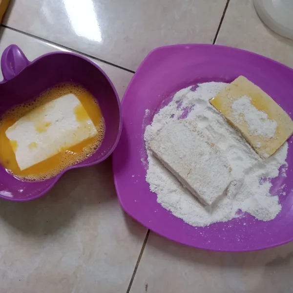 Celupkan tahu dalam telur kocok, baluri dengan tepung putih yang banyak