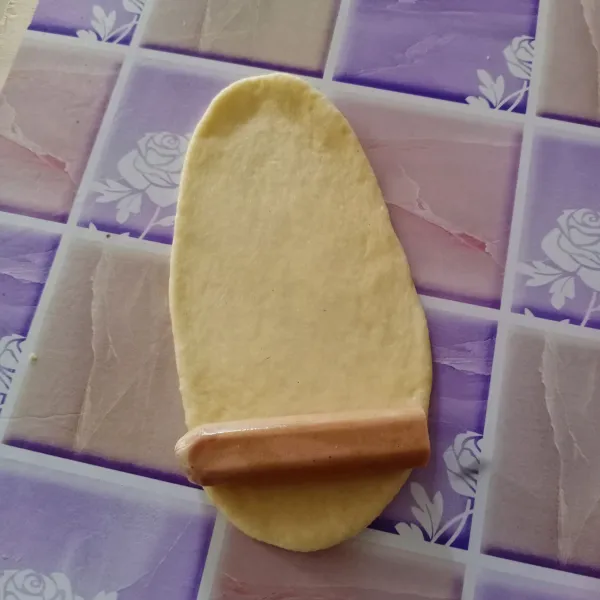 Ambil 1 adonan, gilas memanjang. Beri sosis kemudian gulung.