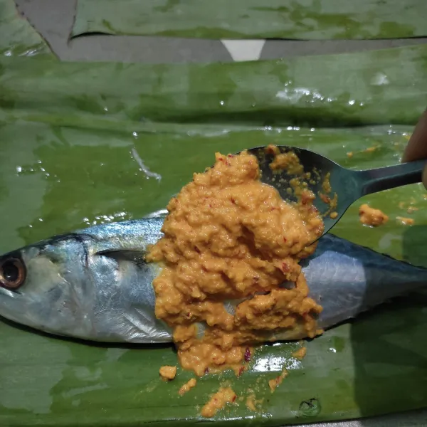 Bersihkan ikan, beri air jeruk nipis, lalu bilas. Letakkan ikan diatas daun pisang, kemudian beri bumbu halus di kedua sisinya.