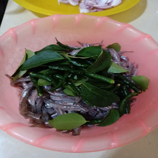 Tambahkan daun kari dan cabai hijau potong ke dalam wadah ikan, aduk rata.