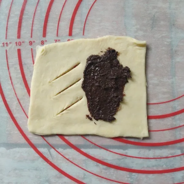 Buat keratan di salah satu sisi lembaran pastry, untuk sisi satunya, olesi dengan selai coklat
