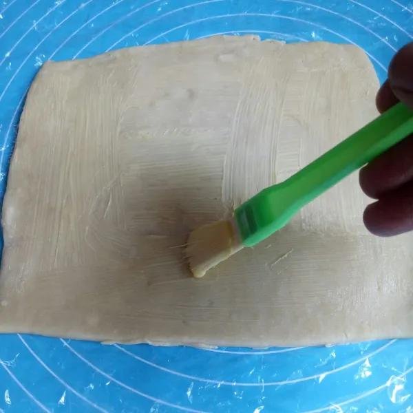 Oleskan mentega pada permukaan kulit pastry
