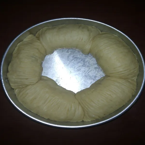 Masukkan adonan roti yang telah digulung ke dalam loyang yang telah diolesi margarin. Istirahatkan kembali selama kurang lebih 15 menit, hingga adonan mengembang menjadi 2x lipat dari ukuran semula. Panaskan oven di suhu 170°C.