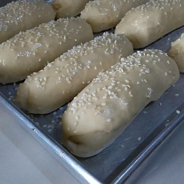 Olesi loyang dengan margarin. Letakan adonan kemudian tutup adonan dengan serbet. Diamkan selama 1 jam. Setelah mengembang olesi permukaan adonan dengan bahan olesan . Taburkan wijen secukupnya.