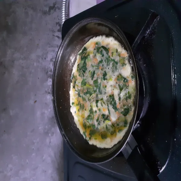 Panaskan minyak goreng. Masukkan adonan omelet. Masak dengan api kecil.